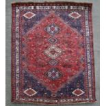 A Persian Qashqai rug with central medallion within a geometric border, on a red ground, 223 by