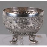 A Burmese white metal bowl decorated with animals, on three fish form legs, 8cms diameter.