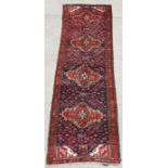 A fine quality Persian hand knotted runner with four central guls on a red ground, 265 by 205cms (
