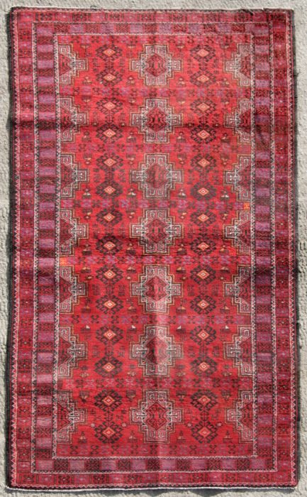 A Persian Balouch woollen rug with stylised guls within multi borders, 205 by 125cms (433).