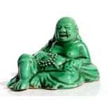 A Chinese shiwan type pottery green glazed figure of a Buddha, 9cms wide.