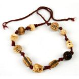 A Japanese necklace of eleven ivory ojime beads to include a signed daruma, a skull, two bells and