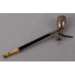 A 19th century white metal opium pipe with ebony shaft and ivory mouth piece, 18cms long.