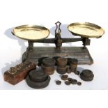 A set of cast iron and brass kitchen scales with associated brass weights.