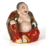 A Chinese ceramic figure of a fat Buddha with glazed robes and bisque body, twin impressed seal