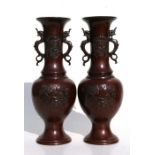 A pair of Japanese Meiji period bronze baluster vases with applied mythical animal handles and