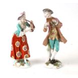 A pair of continental porcelain figures depicting a male and female musician, the largest 27cms