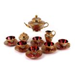 A Bohemian Czech glass tea set in ruby glass with orate gilt and relief foliate decoration