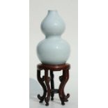 A Chinese pale celadon glaze double gourd vase on stand, six character blue mark to the underside