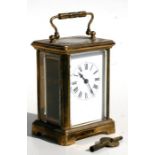 A carriage clock, the white porcelain dial with Roman numerals, in a gilt brass four-pillar case,