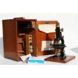 A Dakin Bros. Ltd London black lacquered and brass microscope with various lenses and slides, in a