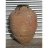 A large terracotta olive jar with banded and crimped decoration, approx 68cms high.