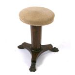 An early 19th century rosewood revolving piano stool on tapering octagonal column and tripod base