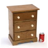 A 19th century stripped pine miniature chest of three long drawers, 35cms wide.