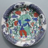 A Turkish / Iznik shallow dish decorated with a figure amongst flowering foliage, 31cms diameter.