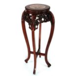 A Chinese hardwood plant stand with inset figured marble top and pierce prunus frieze.