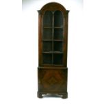 A figured walnut corner display cabinet, the glazed door enclosing a shelved interior with