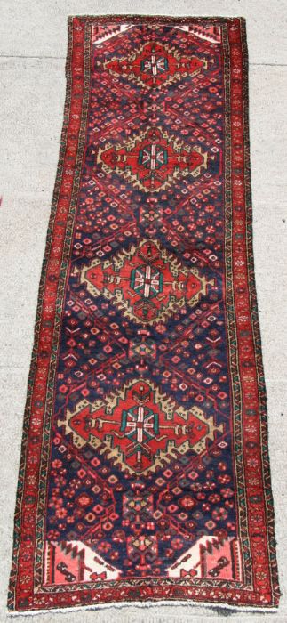 A fine quality Persian hand knotted runner with four central guls on a red ground, 265 by 205cms (