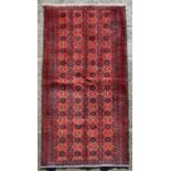 A Persian hand knotted woollen rug, on a red ground, 195 by 100cms (18/126).