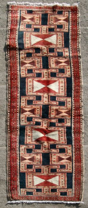 A Persian Tabriz hand knotted woollen runner with geometric design on a red ground, 295 by 75cms (