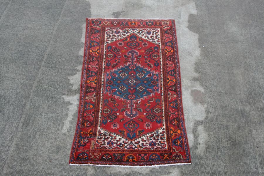 A Persian Hamadan woollen rug with central gul within stylised borders, 205 by 125cms (369).