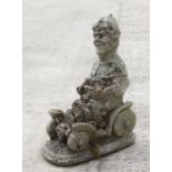 A reconstituted stone garden figure of a gnome riding in a car. 53cm high