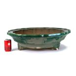 A large Chinese green glazed scalloped edge shallow planter on tripod legs, 66cms diameter.