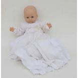 A vintage plastic doll with sleeping eyes, dressed in an Edwardian christening gown.