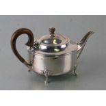 George V Queen Anne style silver teapot of compressed circular form, on oak leaf capped claw feet,