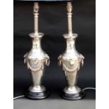 A pair of white coloured metal vase form table lamps with twin lion mask handles and swags, 59cms