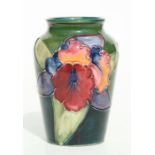 A 1930's Moorcroft pottery vase decorated with orchids on a green ground, paper label to the