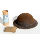 A WWII steel helmet together with a field dressing and other items..