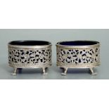 A pair of Indian pierced white metal salts in the Georgian style with claw feet and Bristol blue