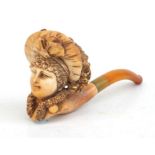 A carved Meerschaum pipe depicting a lady wearing a bonnet, with amber mouthpiece and original