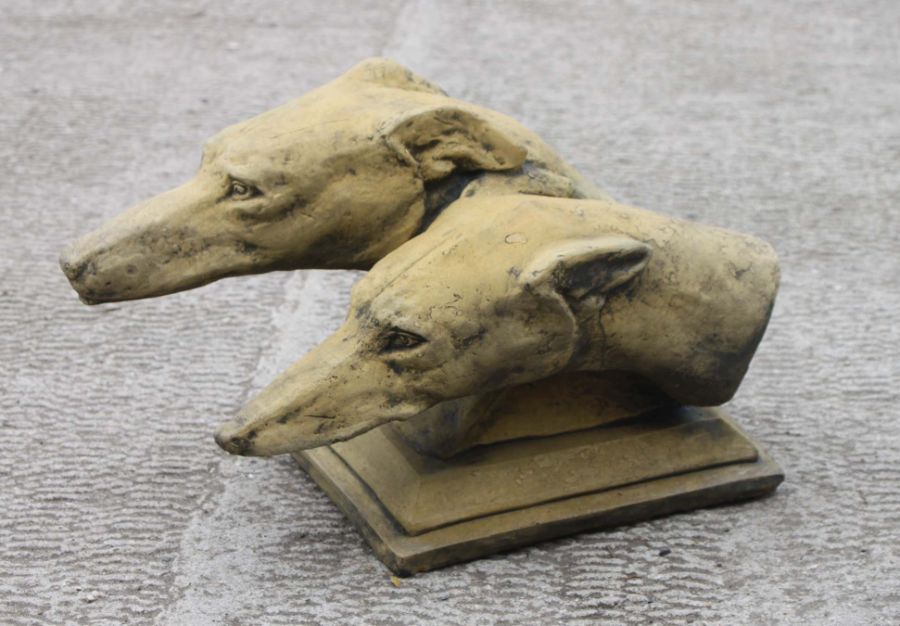 A reconstituted stone garden statue in the form of a pair of greyhound heads, approx 46cms long.