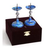 A pair of Chinese white metal and enamel weighted pricket candlesticks decorated with fish on a blue