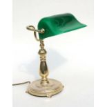 A brass bankers lamp with green glass shade.