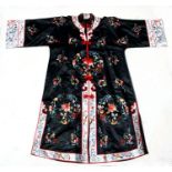 A Chinese silk embroidered jacket decorated with flowers on a black ground, together with a