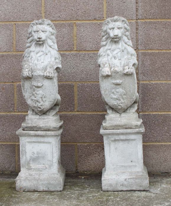 A pair of reconstituted stone rampant lions on square plinths, overall 115cms high.