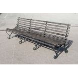 A large wrought iron and slatted wood garden bench