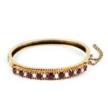 A Victorian yellow metal ruby and pearl bangle, of hinged circular form. 6cm diameter