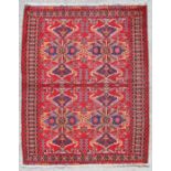 A Persian hand knotted Gonbad rug with butterfly design within stylised borders, on a red ground,
