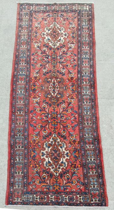 A Persian Azari woollen hand knotted Azari runner with three central guls within geometric floral