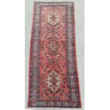 A Persian Azari woollen hand knotted Azari runner with three central guls within geometric floral