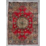 A Persian Tabriz woollen hand made rug with with central foliate gul within floral borders, on a red