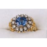 An 18ct gold diamond and sapphire ring set with a large oval pale blue sapphire surrounded by twelve