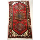 A Persian Hamadan hand knotted woollen rug with stylised design within borders, on a red ground, 163