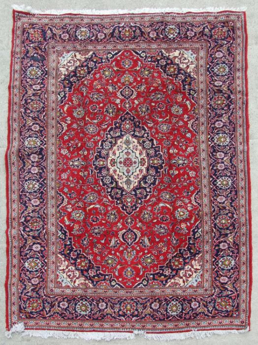 A Persian Kashan woollen hand knotted rug, the central medallion with floral sprays and borders, 290