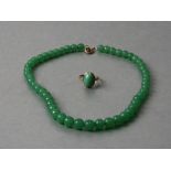 A child's jade like graduated bead necklace. 34cm long together with a yellow metal child's ring set