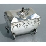 A George V silver tea caddy of rectangular tapering form on 'C' scroll legs and hoof feet, Sheffield